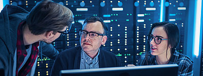 Junge IT-Mitarbeitende zeigen ihrem Chef im Serverraum, wie sie die Netzwerksicherheit optimieren