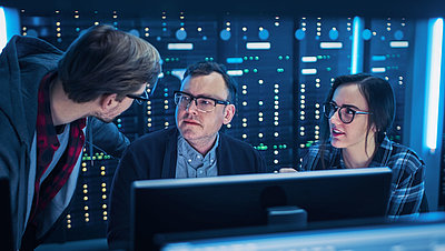 Junge IT-Mitarbeitende zeigen ihrem Chef im Serverraum, wie sie die Netzwerksicherheit optimieren