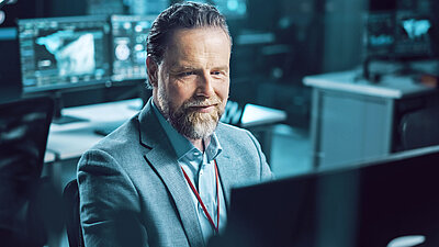 Bärtigen Büro-Mitarbeiter freut sich an PC über sein sicheres Netzwerk