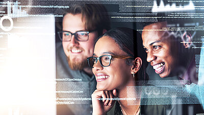 Drei IT-Mitarbeitende schauen erfreut auf Bildschirm