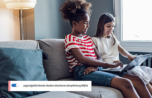 Zwei Mädchen sitzen auf der Couch mit Tablet