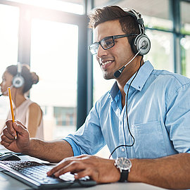 Personnel de vente amical avec casque répondant aux appels des clients au bureau