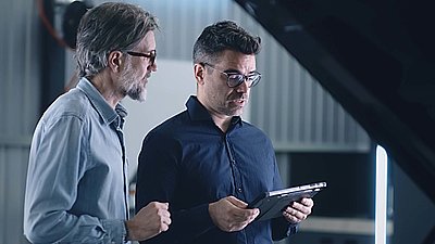 Zwei Männer beraten sich über die Sicherheit einer Cloud mit einem Tablet in der Hand