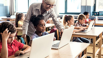 Kinder und Lehrperson beim digitalen Unterricht