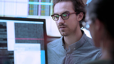 IT-Mitarbeiter prüft Programmiercode auf PC-Screen auf Hackerangriffe